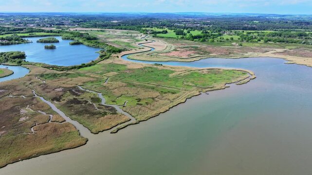 Aerial tracking shot of Salt marsh and Reed beds at mouth of the River Piddle near Poole, Dorset, UK