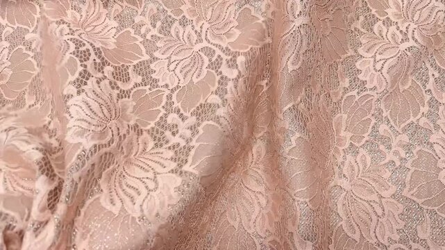 The exquisite dusty pink lace fabric features an intricate floral pattern woven onto a shimmering silver lurex base. This premium lightweight material is ideal for luxury bridal and evening wear.