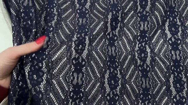 The elegant navy blue lace fabric features an intricate floral and geometric pattern highlighted by shimmering silver threads. This lightweight textile is perfect for high end evening wear.