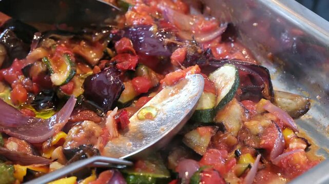 Close up of Olive Oil Drizzling over Fresh Ratatouille Vegetables Cooking in a Baking Tray 