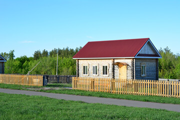 Obraz premium Wooden house with red roof and wooden fence in a rural area copy space