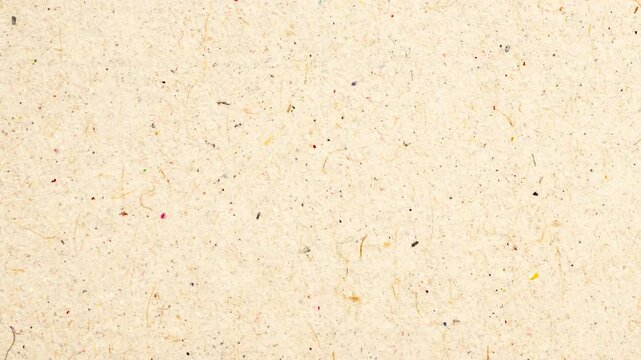 A close-up view of a beige textured surface with small specks and spots