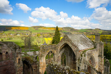 Naklejka premium A view from an elevated vantage point of the ruins of Melrose Abbey in Scotland, nestled in the rolling hills of the Scottish Borders