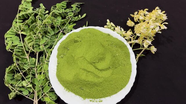 organic moringa powder with green leaves and drumstick flowers natural herbal concept