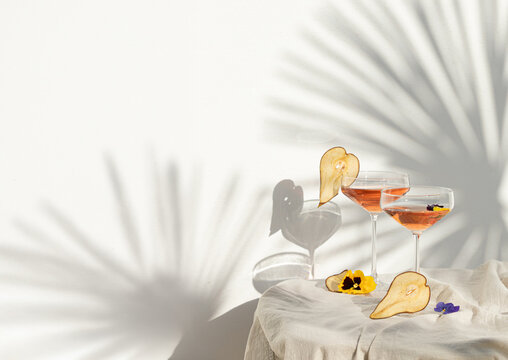 Two rose wine glasses with summer cocktails and dried fruit appetizers