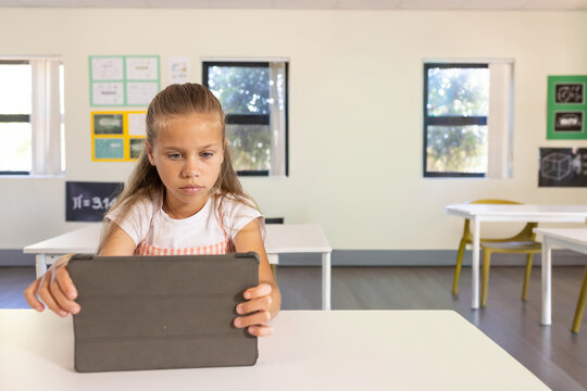 Female student tapping tablet at desk in classroom, generating animated math charts for learning