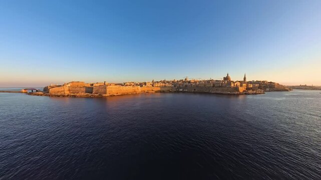 Wide, panoramic aerial video of La Valetta in Malta, at sunset from the perspective of Sliema