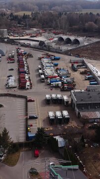 Vertical screen Aerial Truck Yard Warszawa Rows Of Parked Trucks And Trailers At Industrial Depot, Logistics Crews Preparing Fleet, Cargo Containers And Service Vehicles Lined In Parallel