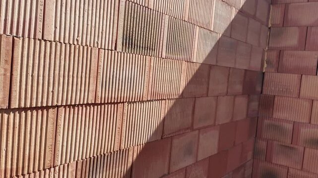 Close-up view of a building wall constructed with hollow clay blocks. Detailed texture and pattern of porous ceramic bricks forming a structural wall, showcasing construction materials and techniques.