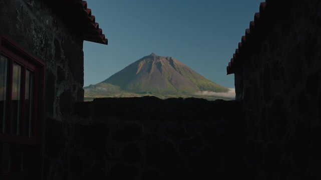 Cinematic Wide Shot of Mount Pico Volcano Framed by Silhouetted Traditional Basalt Stone Houses Under a Clear Twilight Sky, Pico Island, Azores