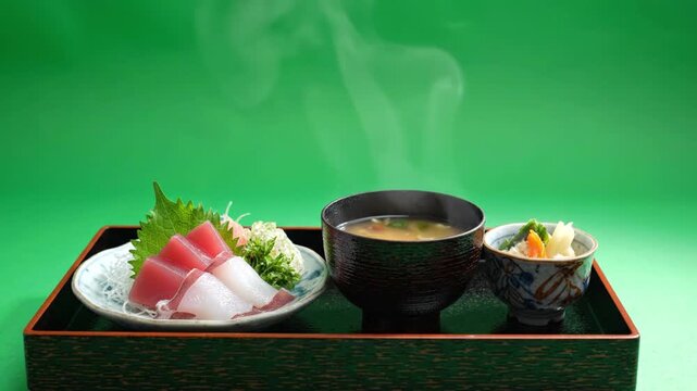 Fresh sashimi plate with tuna and squid, shredded radish and shiso, steaming miso soup and pickled vegetable side dish lacquer tray appetizing Japanese cuisine seafood garnish presented with calm