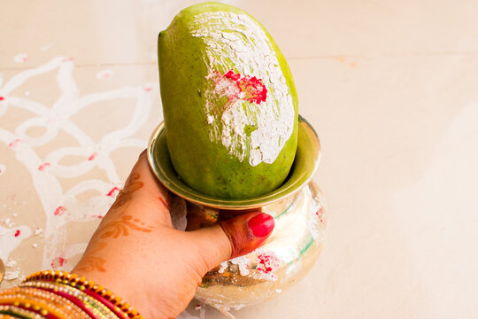 hand holding lota and mango for worshiping the banyan tree during vat savitri puja.	