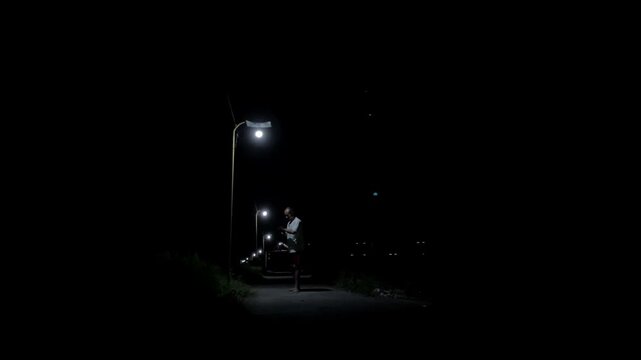 4K ground view of a man wrapping his hands under a street lamp in a dark, mysterious alley. Gritty preparation for shadow boxing training.