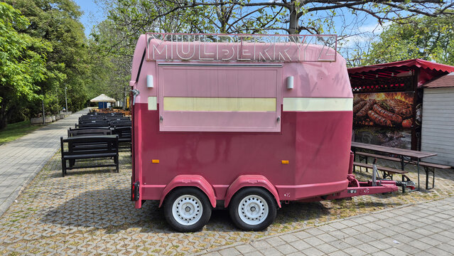 A pink and burgundy horse trailer converted into a mobile food cart named Mulberryz, parked on a paved outdoor walkway. Picture taken on May 8, 2026 in Bucharest, Romania.