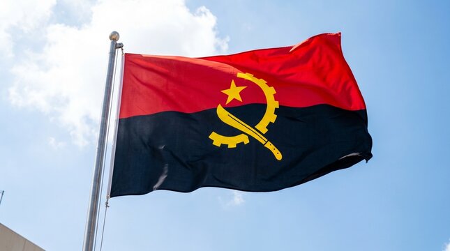 The Angolan flag waves beneath a bright blue sky, symbolizing strength, independence, and unity through its red, black, and yellow emblem of revolution and progress.