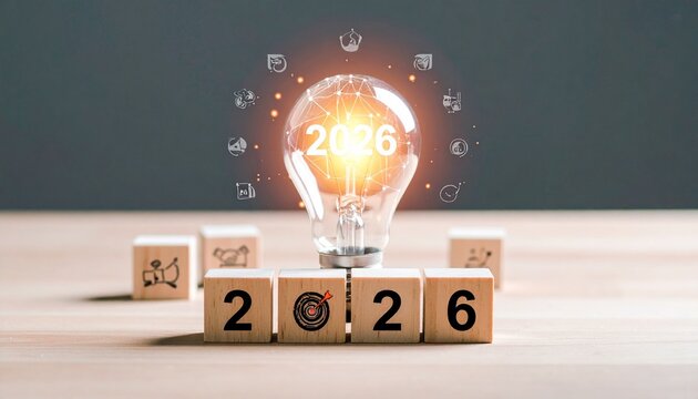 Glowing light bulb with &ldquo;2026&rdquo; illuminated, surrounded by icons and wooden blocks, symbolizing innovation, creativity, and future goals.