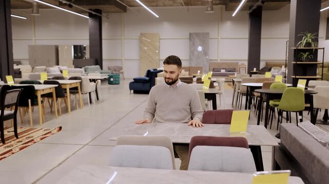 Male customer considering new dining furniture in modern showroom, shopping for home interior design