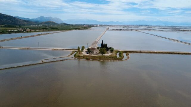 Aerial rotating view of stone chapel surrounded by shallow lagoon water