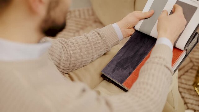 Man choosing fabric samples for home interior design, selecting textile swatches for furniture upholstery