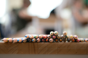 Naklejka premium Colored pencils arranged on a wooden table with soft blurred classroom background