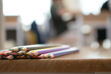 Naklejka premium Colored pencils arranged on a wooden table with soft blurred classroom background