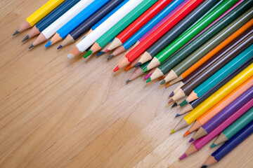 Naklejka premium Top view of colorful pencils lined on a wooden surface for education