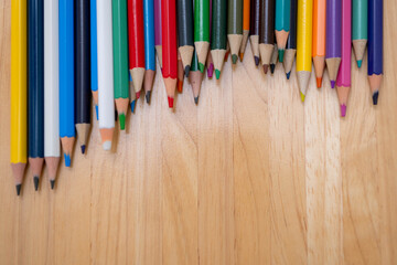 Naklejka premium Top view of colorful pencils lined on a wooden surface for education