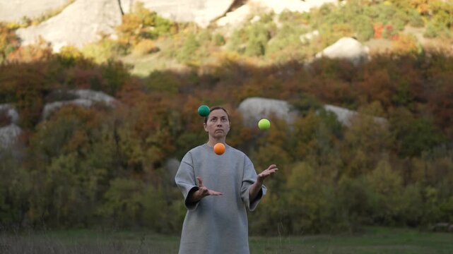 Skilled Juggling Performance Practicing Woman Throws Balls Against Autumn Mountain Backdrop
