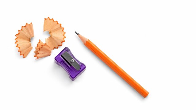 Translucent purple pencil sharpener with orange pencil and fan shaped shavings for stationery flat lay