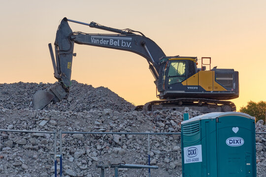 Heavy Excavator On Demolition Site With Rubble Pile And Portable Toilet At Sunset, Construction Industry, Urban Renewal, Development, Machinery