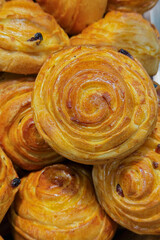 Fototapeta premium Close up of delicious golden brown glazed spiral sweet rolls with baked raisins arranged for display