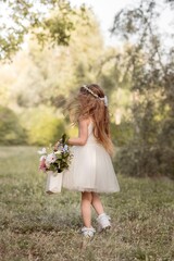 Obraz premium Little girl walking with flower bouquet in sunny park