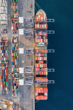 Overhead aerial view of a super container ship being unloaded by crynes in a commercial cargo terminal