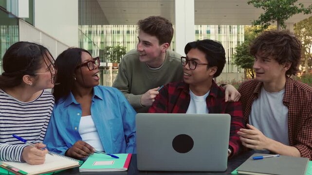 Diverse group of students collaborating on laptop outdoors