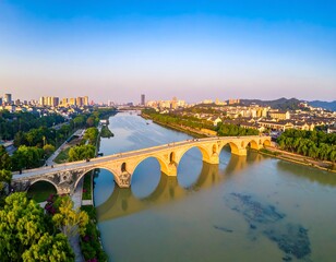 Naklejka premium Historic Stone Arch Bridge Spanning Calm River in Sunny City Landscape