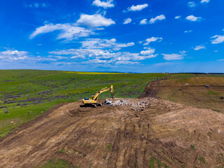 Construction work taking place on a rural site with heavy machinery moving dirt under a blue sky and clouds © DSMT