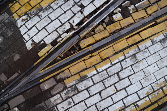 Crossing tram tracks embedded in yellow and white paving stones