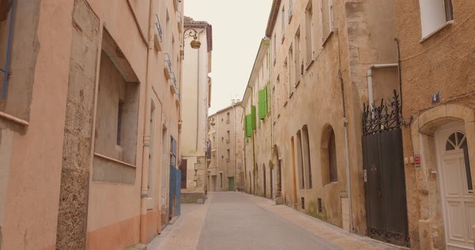 Walking along a quiet narrow street lined with old stone buildings in Narbonne