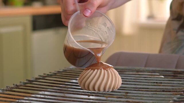 Beautiful mousse cake is drizzled with mirror glaze on grate. Closeup Glazed mousse dome dessert with caramel chocolate decorated with dripping shiny ganache poured drips. Smooth sponge biscuit