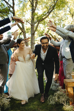 Happy wedding couple walking through joyful guests in outdoor celebration