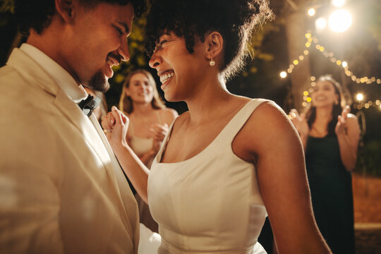 Smiling bride and groom dancing at an intimate evening wedding celebration outdoors