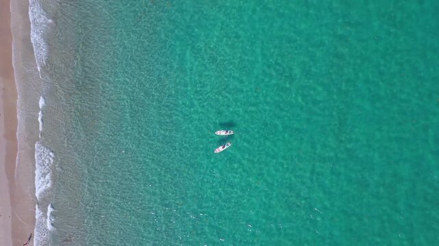 Two paddle boarders float peacefully on a stunning blue green ocean near the shore in Deerfield Beach Florida captured from above by a drone