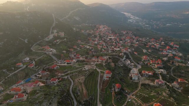 Aerial view of Douma village in Lebanon showing clustered homes, terraced land, and winding roads across a scenic mountain setting.