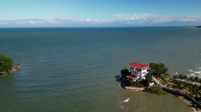 Stunning aerial flyover of Roca Encantada heritage house along the Guimaras coastline in the Philippines with surrounding ocean and tropical scenery