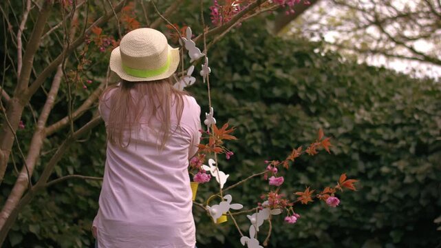Woman wearing Easter bonnet and sits by easter decorations on blossom tree