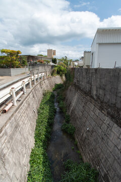 道と壁の間を通る田舎の住宅地の細い川