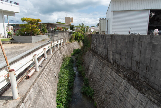 道と壁の間を通る田舎の住宅地の細い川