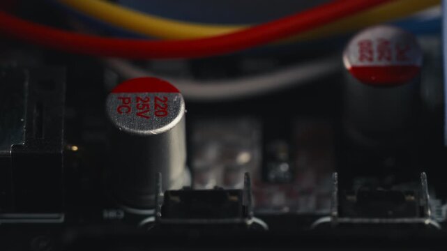 Macro slider shot of a disassembled UPS circuit board. Selective focus moving over blue thermal pad, wires, and various micro electronic components on PCB surface. High-tech engineering background.