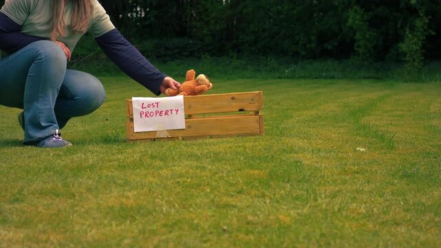 Picking up lost children toy teddy bear from lost property box