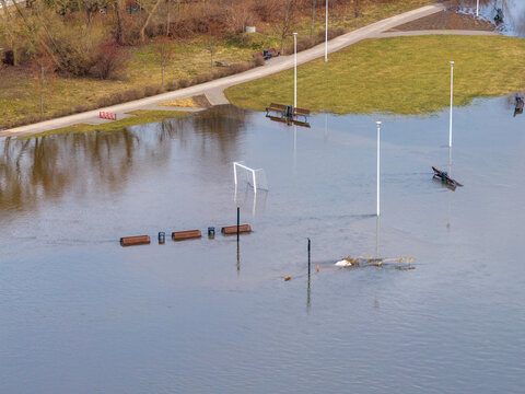 Aerial view of a flooded park with a soccer goal, benches, and lamp posts partially submerged in water during a spring flood in Kedainiai, Kaunas County, Lithuania.